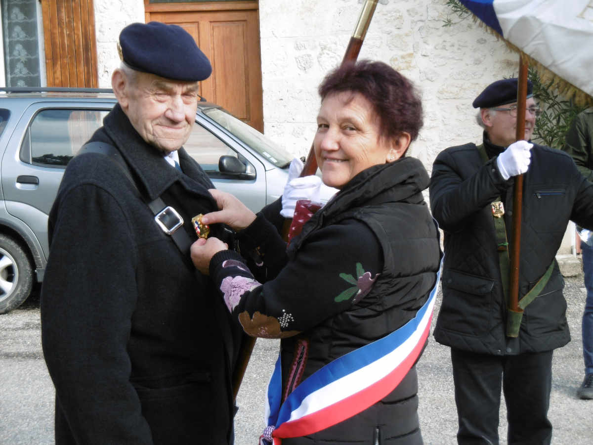Giselle Mutti attache l'insigne honorifique au revers de la veste de Théo Hrynkiw